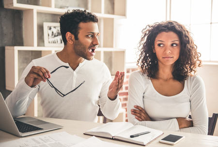 Beautiful young Afro American business couple working at home. Man is scolding his wifeの写真素材