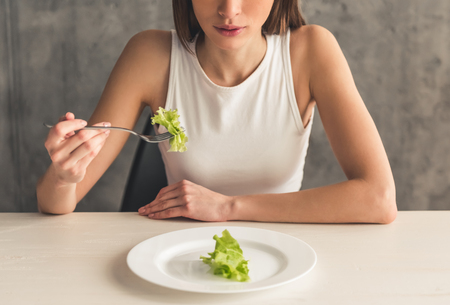 Eating disorder. Cropped image of girl eating lettuce