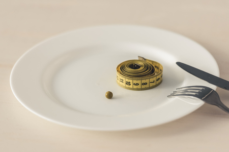 Weight loss concept. Plate with a tape measure on itの写真素材