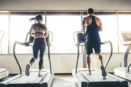 Back view of beautiful sports people running on a treadmill in gymの写真素材