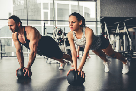 Attractive sports people are working out with fitness balls in gymの写真素材