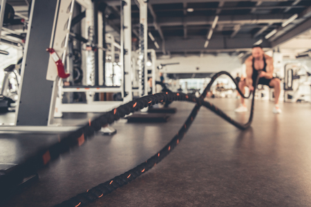 Handsome muscular man is working out with cable in gymの写真素材