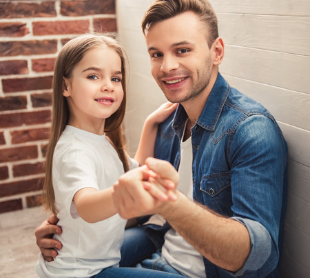 Charming little girl and her handsome young dad are dancing, looking at camera and smilingの写真素材