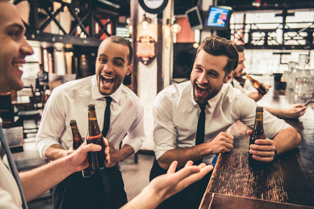 Handsome businessmen are drinking beer, talking and laughing while resting at the pubの写真素材