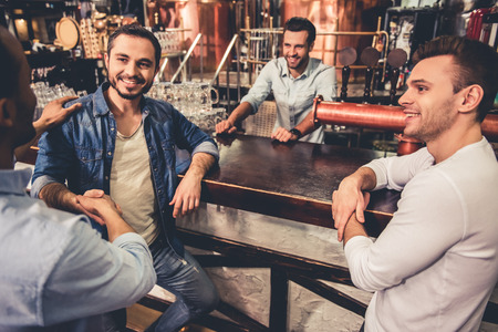 Handsome guys are talking and smiling while resting in pubの写真素材