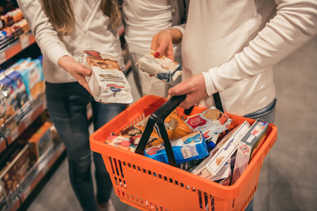 Cropped image of beautiful mature couple and their pretty daughter doing shopping in supermarketの写真素材