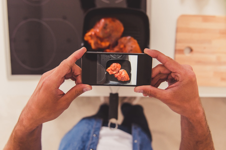 Cropped image of handsome man taking photo of meal using a smart phoneの写真素材