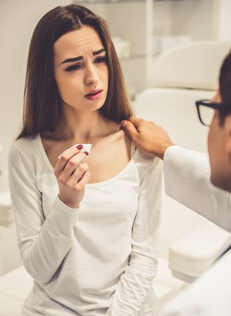 Beautiful woman is crying and handsome beautician is calming her during the consultationの写真素材
