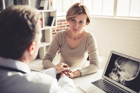 Beautiful mature woman is listening to the doctor during the consultationの写真素材