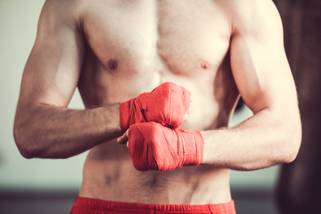 Cropped image of handsome bearded boxer with bare torso wrapping his hands, ready to fight at the fight clubの写真素材