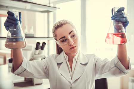 Beautiful medical doctor in protective glasses is working with a test tubes at the labの写真素材
