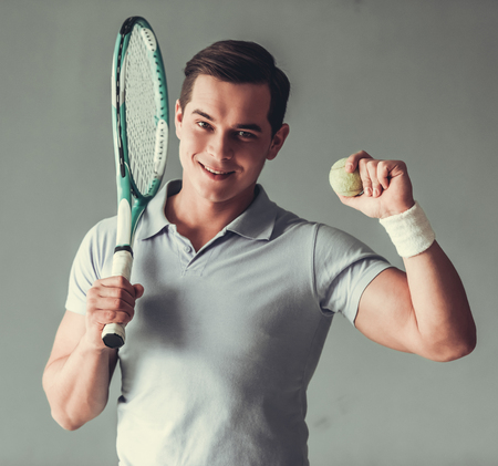 Young sports man. Man tennis player on a gray background.の写真素材