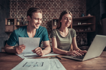 Family business. Young couple working with documents using laptop at home in the kitchen.の写真素材