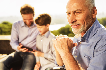 An old man in a wheelchair posing against his son and grandson