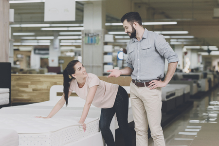 A couple chooses a mattress in the store. A woman points at one of them. A man is standing byの写真素材