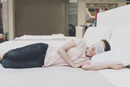 The woman put on a blindfold on her eyes and fell asleep on the bed in the storeの写真素材