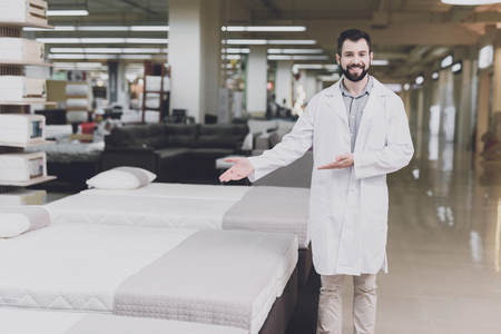 Male orthopedic posing against the background of mattresses and beds and showing a hand on themの写真素材