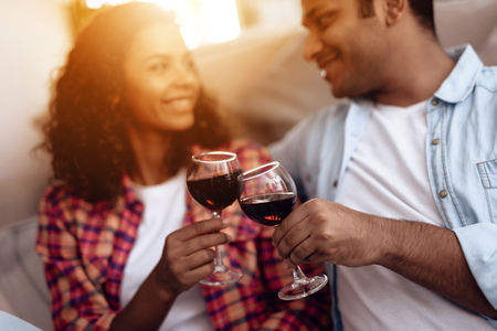 Black man and woman are sitting on the couch. A man and a woman embraced and drank wine.の写真素材