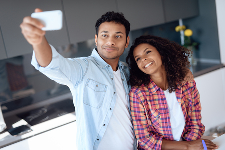 Black man and woman in the kitchen at home. They prepare and make selfi while preparing food.の写真素材