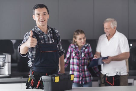 The plumber is posing in the kitchen. He shows his thumb up and smiles.の写真素材