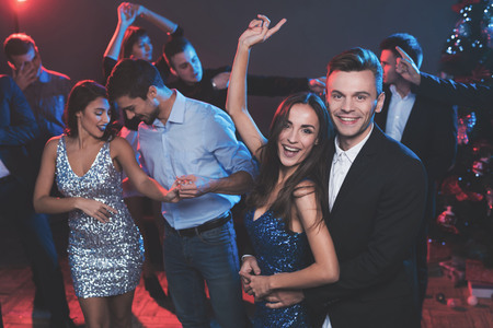 People have fun at the New Years party. In the foreground, a guy and a girl are dancing.