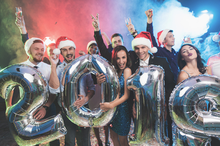 Young people at the New Year party are posing with brilliant figures in 2018. The guys are having...