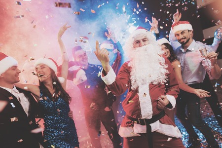 A man dressed as Santa Claus has fun at a New Year party. Together with him have fun friends.の写真素材