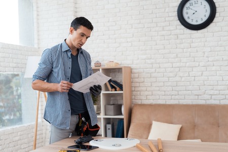 The young man tries himself to fold his coffee table and stools.の写真素材