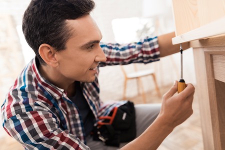 The young man tries himself to fold his bookcase.の写真素材