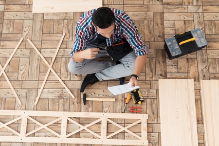 The young man tries himself to fold his bookcase.の写真素材