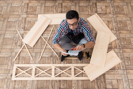 The young man tries himself to fold his bookcase.の写真素材