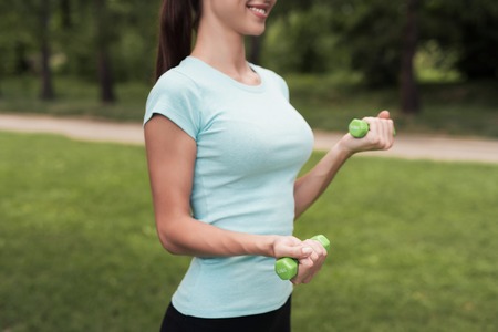 Girl in the park doing exercises with dumbbellsの写真素材
