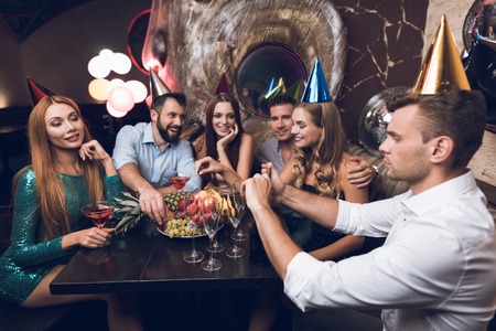 The man opens champagne to drink with his friends. They sit in the club at the table and rest after the dance.の写真素材
