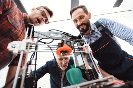 Three engineers are delighted to see how the 3d printer printed an apple model.の写真素材