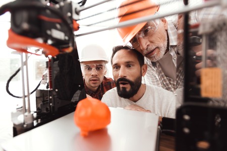 Three men are working to prepare printed model on the 3d model of the heart. They are satisfied with the result.の写真素材