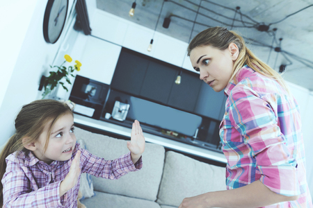 The little girl is frightened and protected from babysitting. She curses the girl and threatens her with a finger.の写真素材