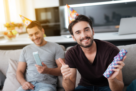Men in birthday hats are showing to each other presents.の写真素材
