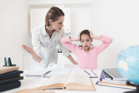 Mom helps my daughter do her homework in the kitchen.の写真素材