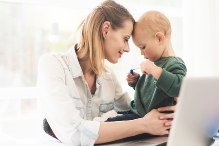 A woman works during maternity leave at home. A woman works and cares for a child at the same time.