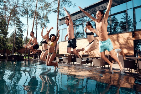 Young guys and girls jump into the pool.の写真素材