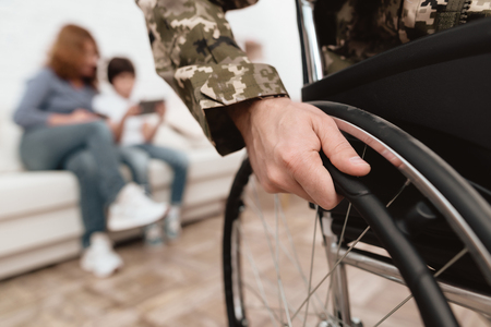 Veteran in wheelchair returned from army. Close-up photo veteran in a wheelchair. Wheelchairs and hands in military uniform.の写真素材
