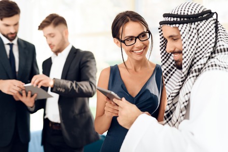 A girl shows something to a man in arabic clothes on a tablet.の写真素材
