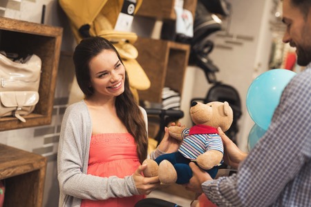A pregnant woman together with a man choose a teddy bear.の写真素材