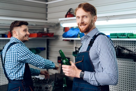 Father and son work at the auto service. Two mechanics work with the details of the car.の写真素材