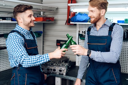 Father and son work at the auto service. Two mechanics work with the details of the car.の写真素材