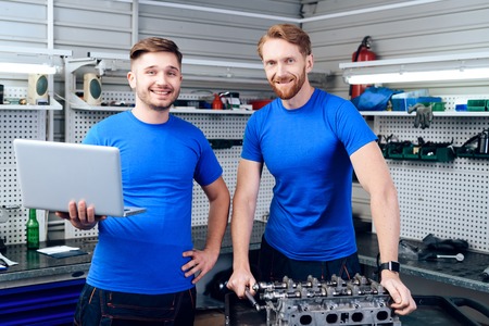 Father and son work at the auto service. Two mechanics work with the details of the car.の写真素材
