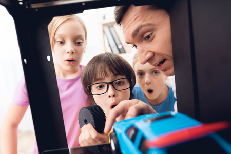 Children print different items on a 3d printer with a teacher.