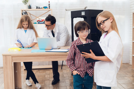 Children print different items on a 3d printer with a teacher.の写真素材
