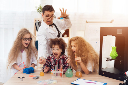 Children in white coats do chemical experiments during the lesson in the classroom.の写真素材