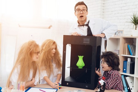 Children print different items on a 3d printer with a teacher.